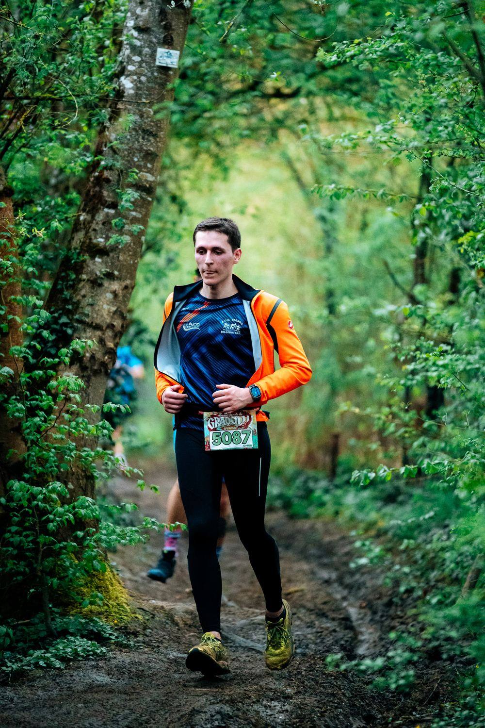 Coureur en veste orange sur le sentier